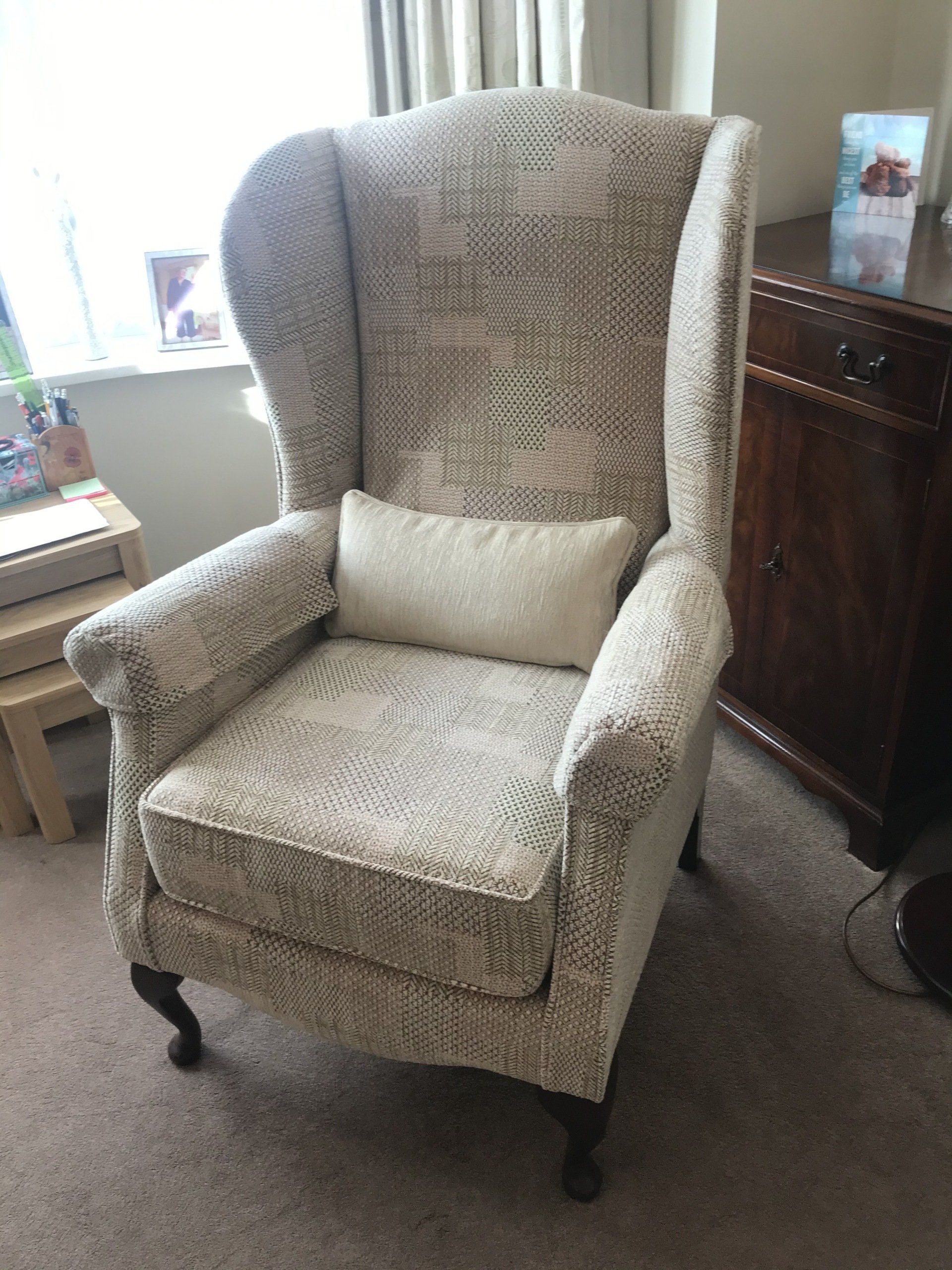 Light coloured armchair in front of a window