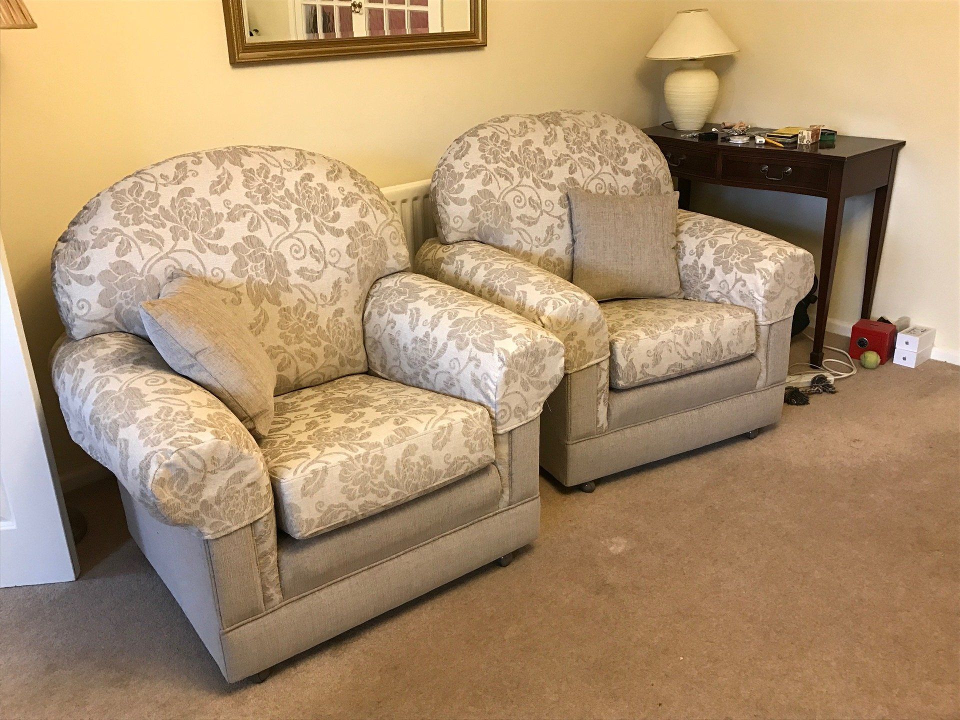 Pair of matching armchairs with light grey patterned upholstery and a mirror behind them