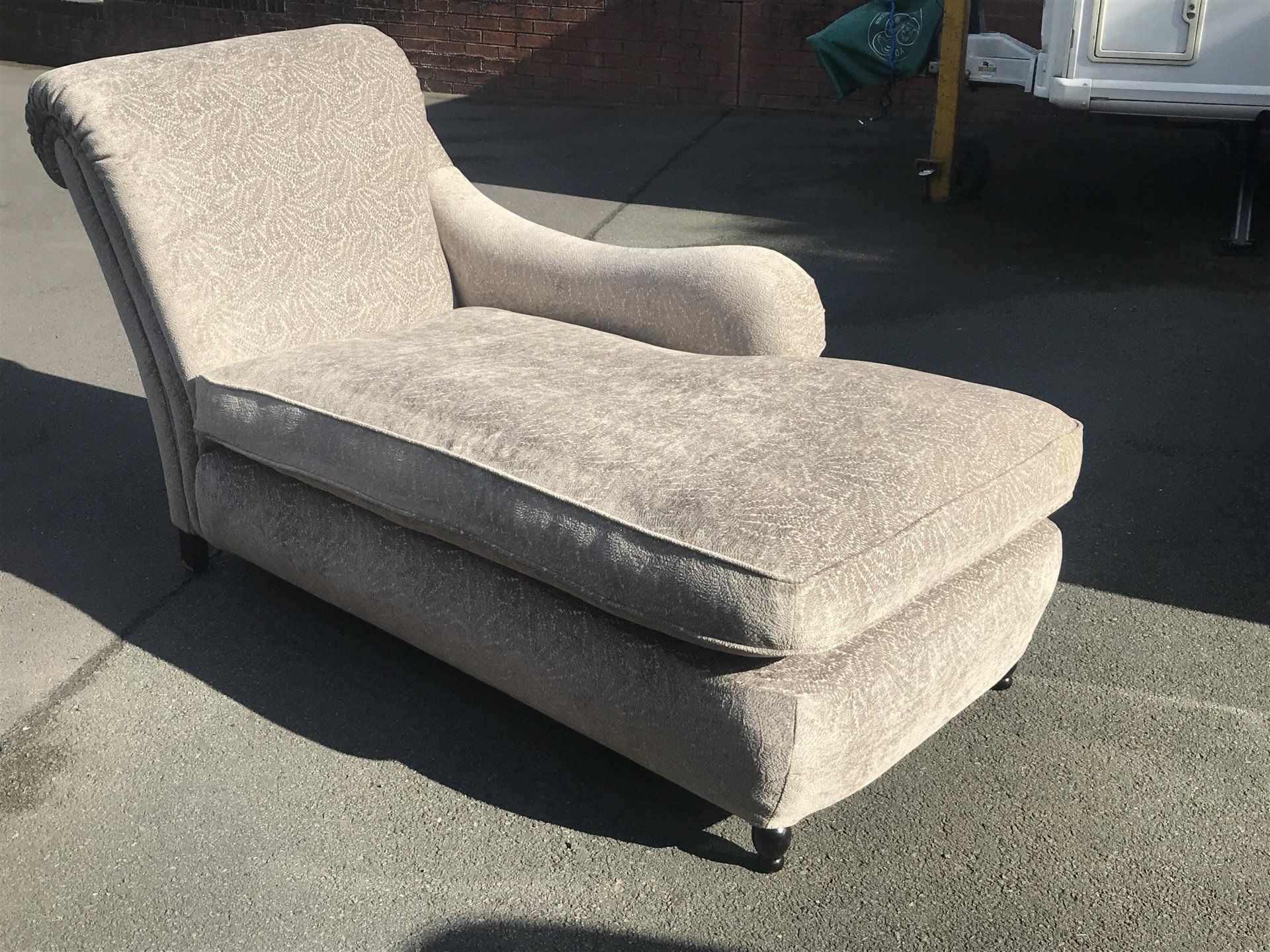 A light coloured chaise lounge outside in sunlight