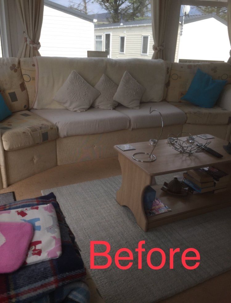 A large light coloured sofa with various cushions and a small wooden coffee table