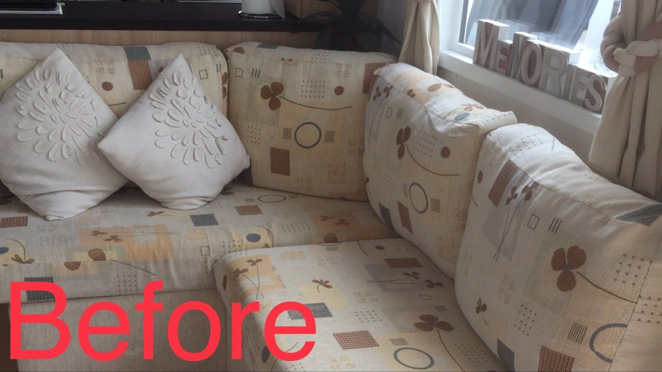 Close up of a sofa in cream fabric with various patterns on it and a white cushion