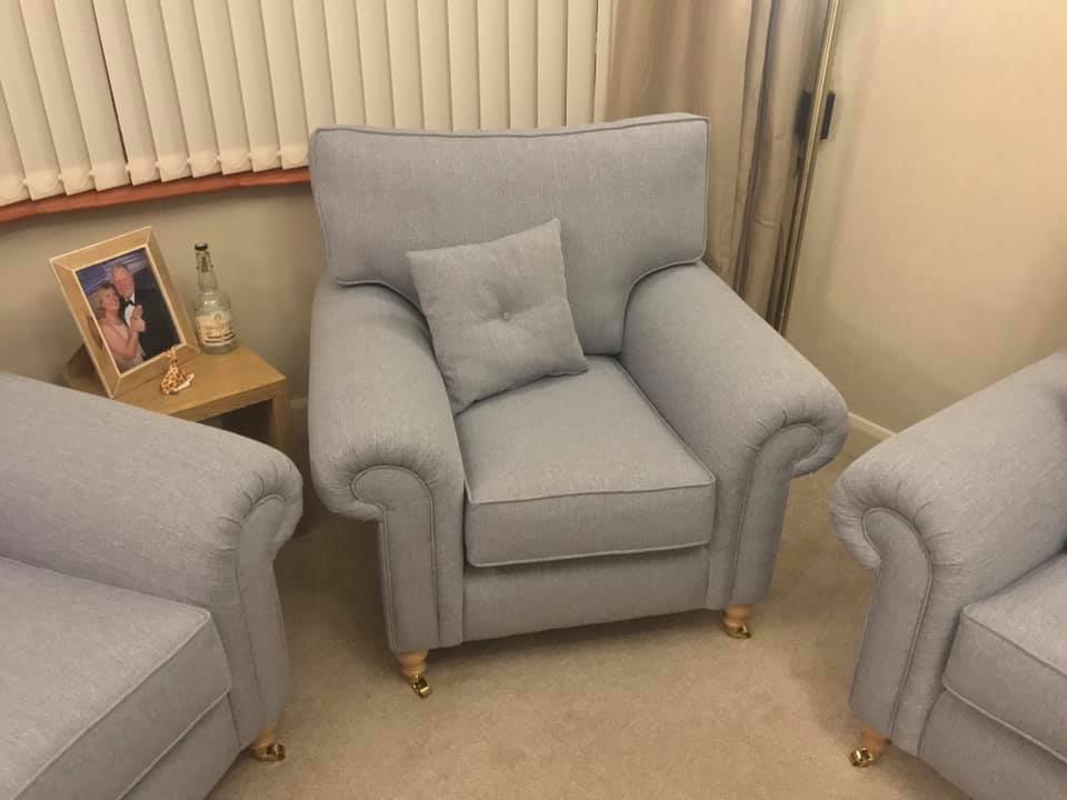 Three grey armchairs in a room with cushions