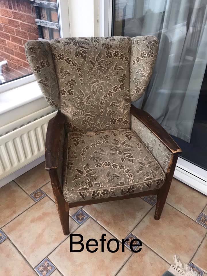 An old armchair with scuffed wooden arms and a grey floral fabric