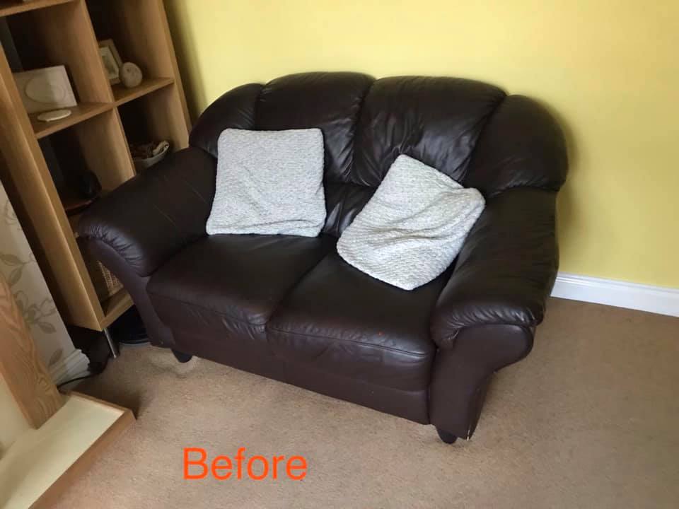Tired looking brown leather sofa with white cushions against a yellow wall
