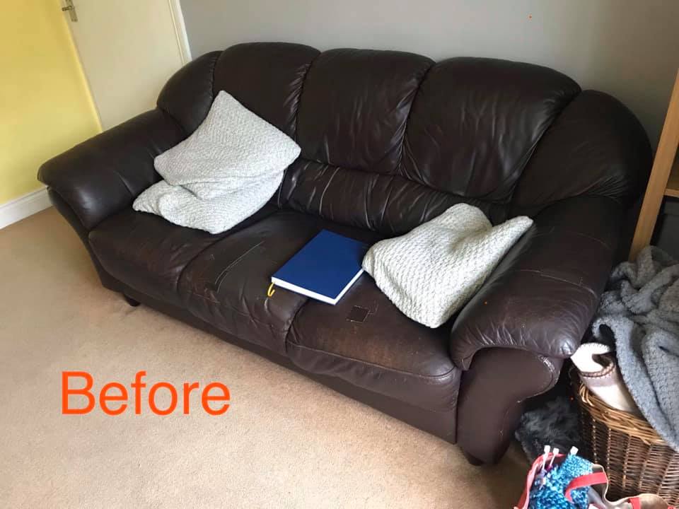 Tired looking brown leather sofa with white cushions and a blue book on it