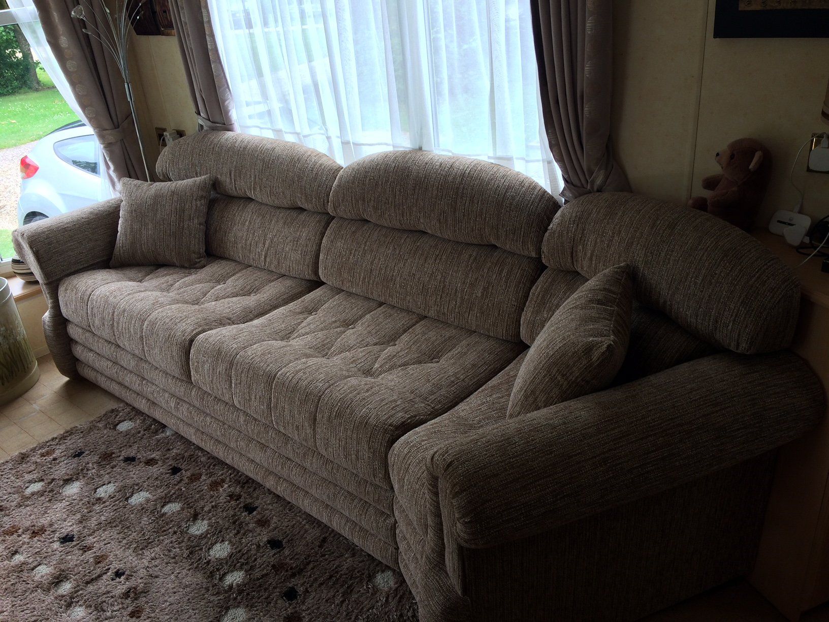 Small grey sofa on a carpet in front of a window