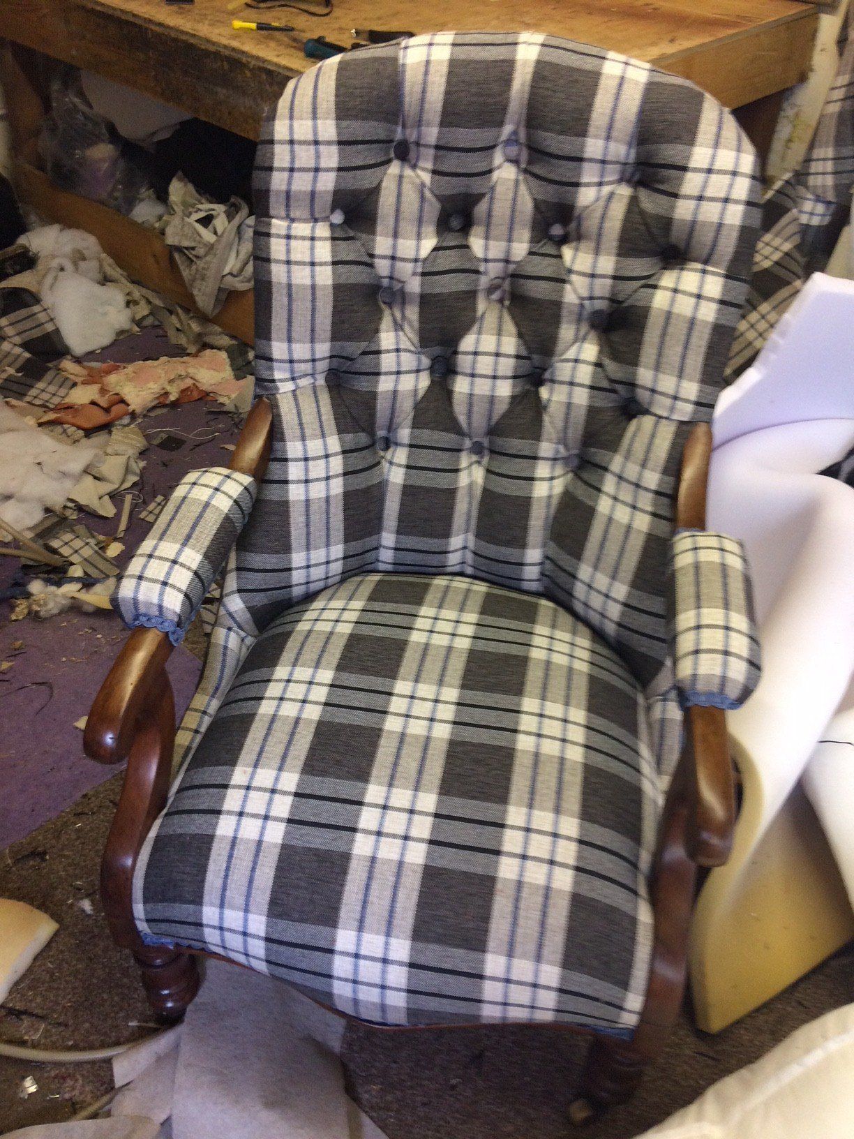 Front view of blue and white check patterned chair with wooden arms