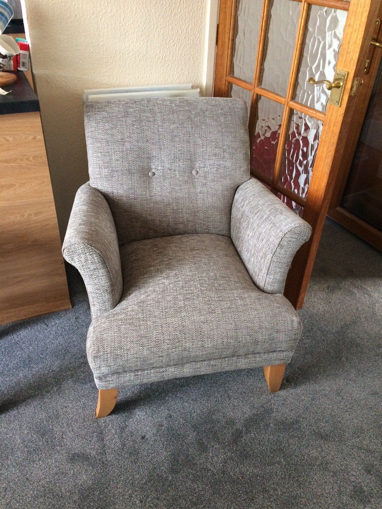 Small grey armchair in a carpeted room