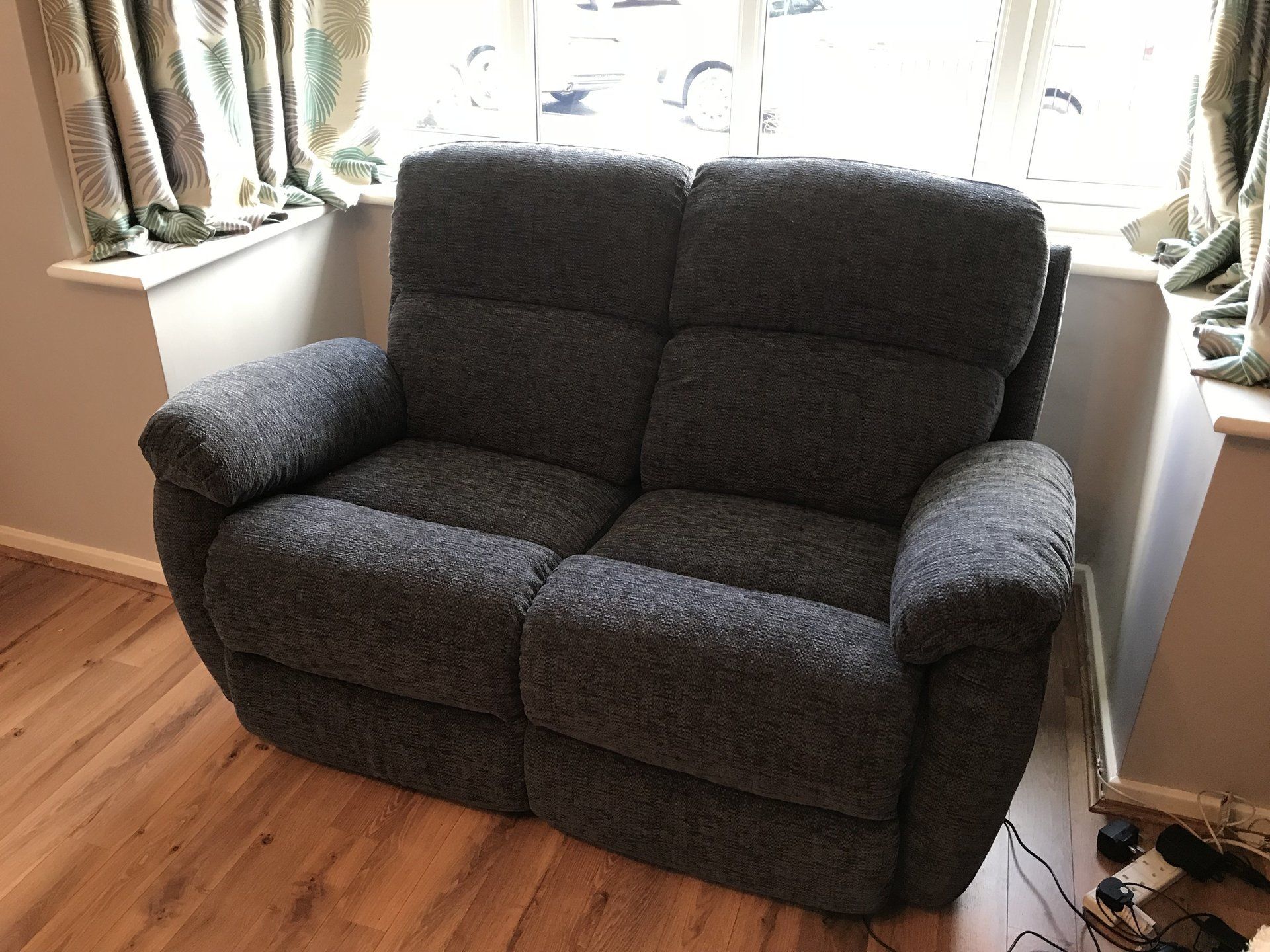A small black sofa next to a window
