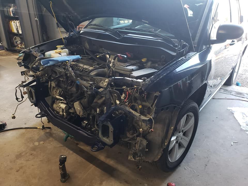a black car with the hood up is being worked on in a garage .