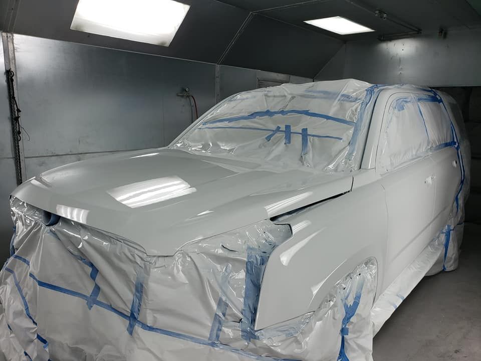 a white car is covered in plastic wrap in a paint booth .