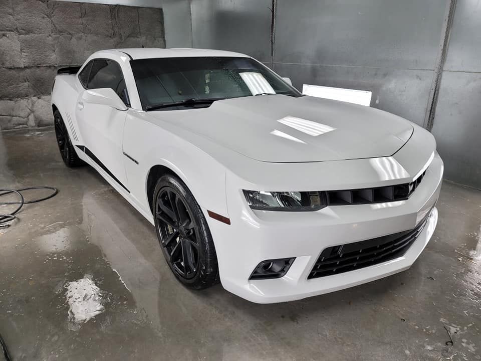 a white car is parked in a garage next to a wall .