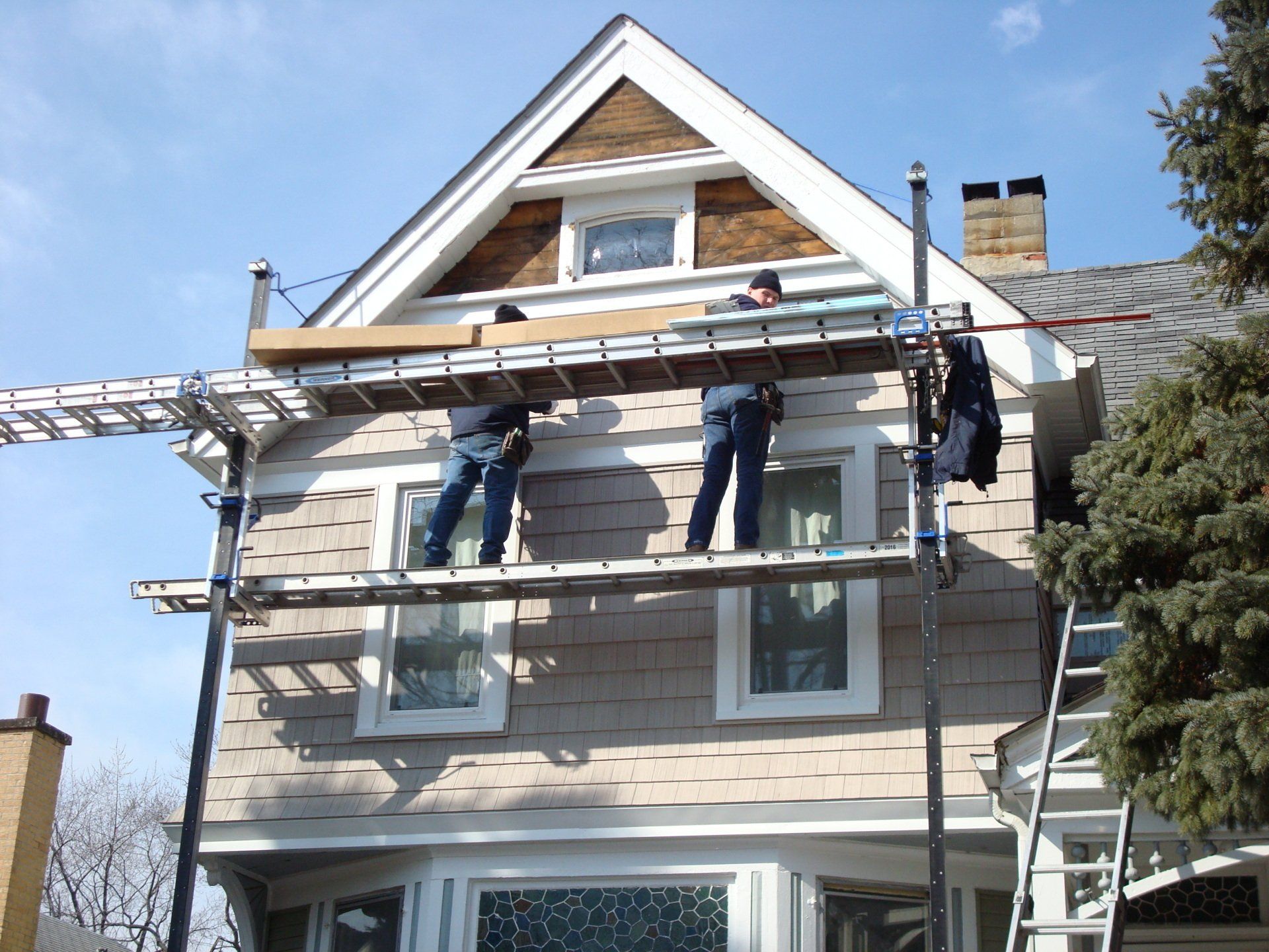 Two men are working on the side of a house