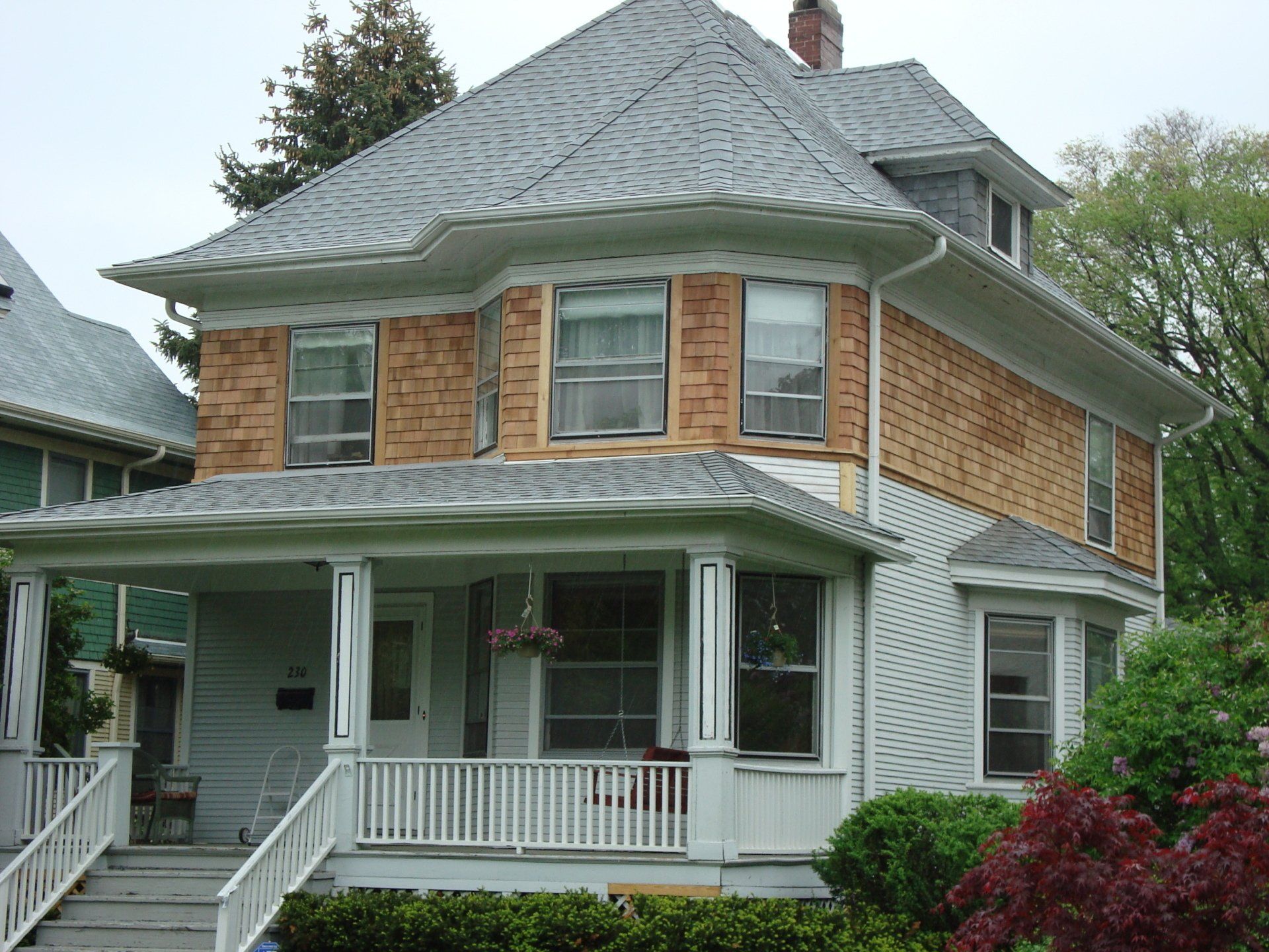 A white house with a gray roof and a porch