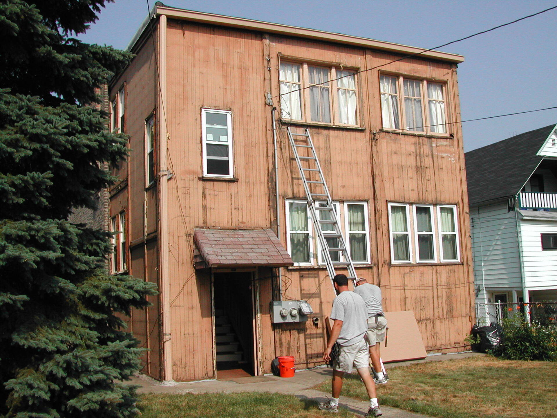 Two men are walking in front of a large wooden house