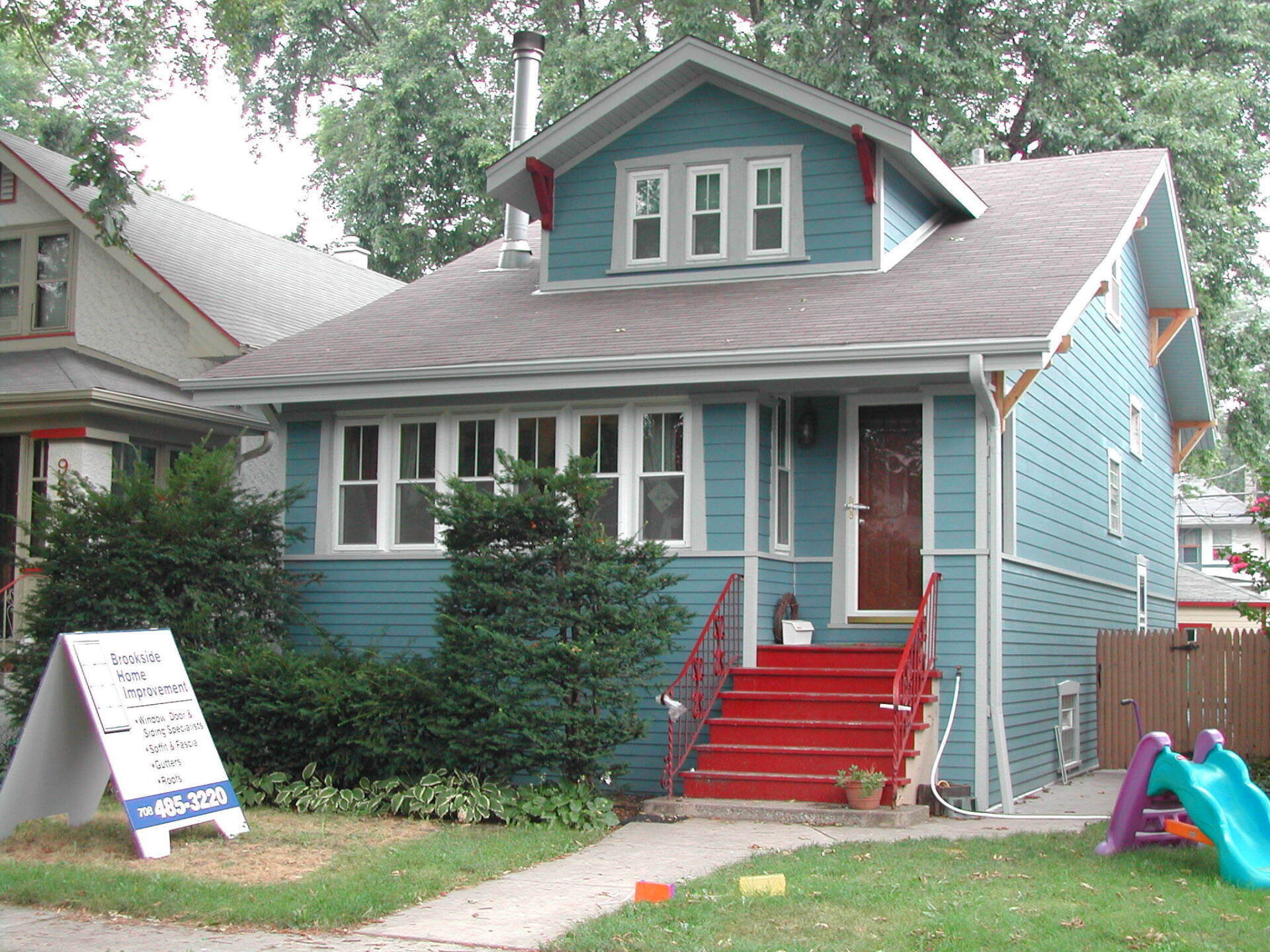 A blue house with red stairs is for sale