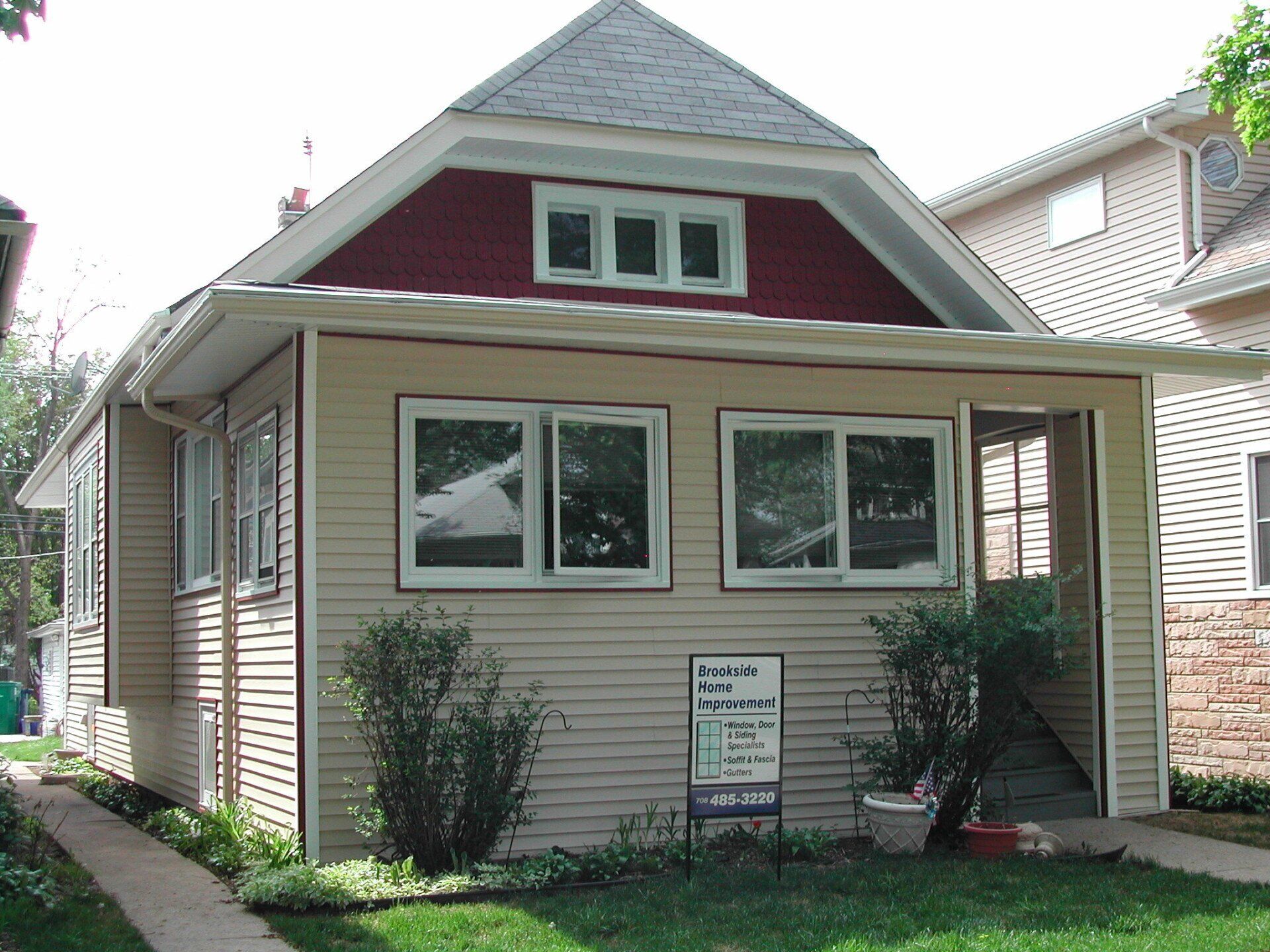 A house with a red roof has a sign in front of it that says 
