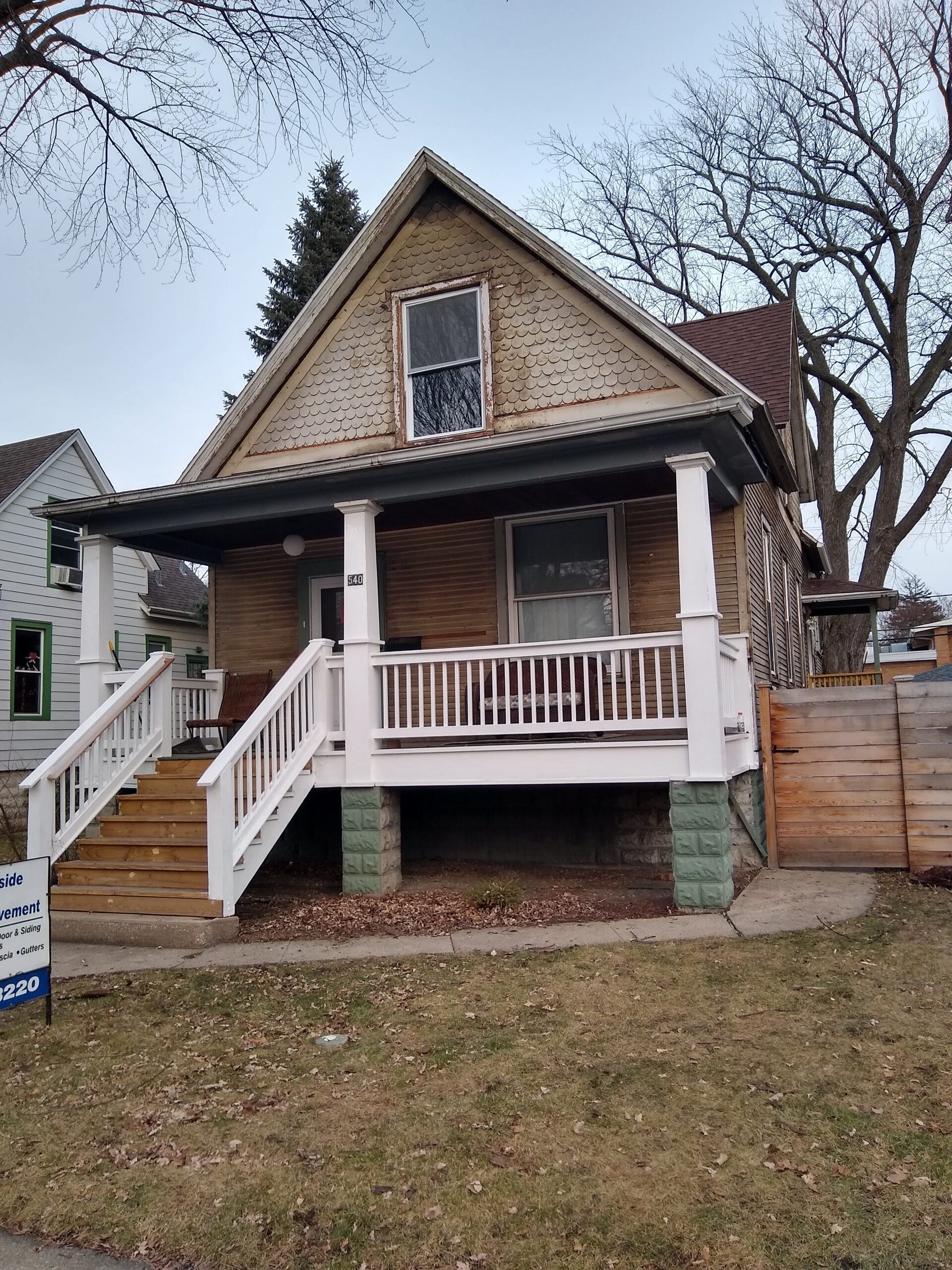 A brick house with a porch and stairs is for sale.