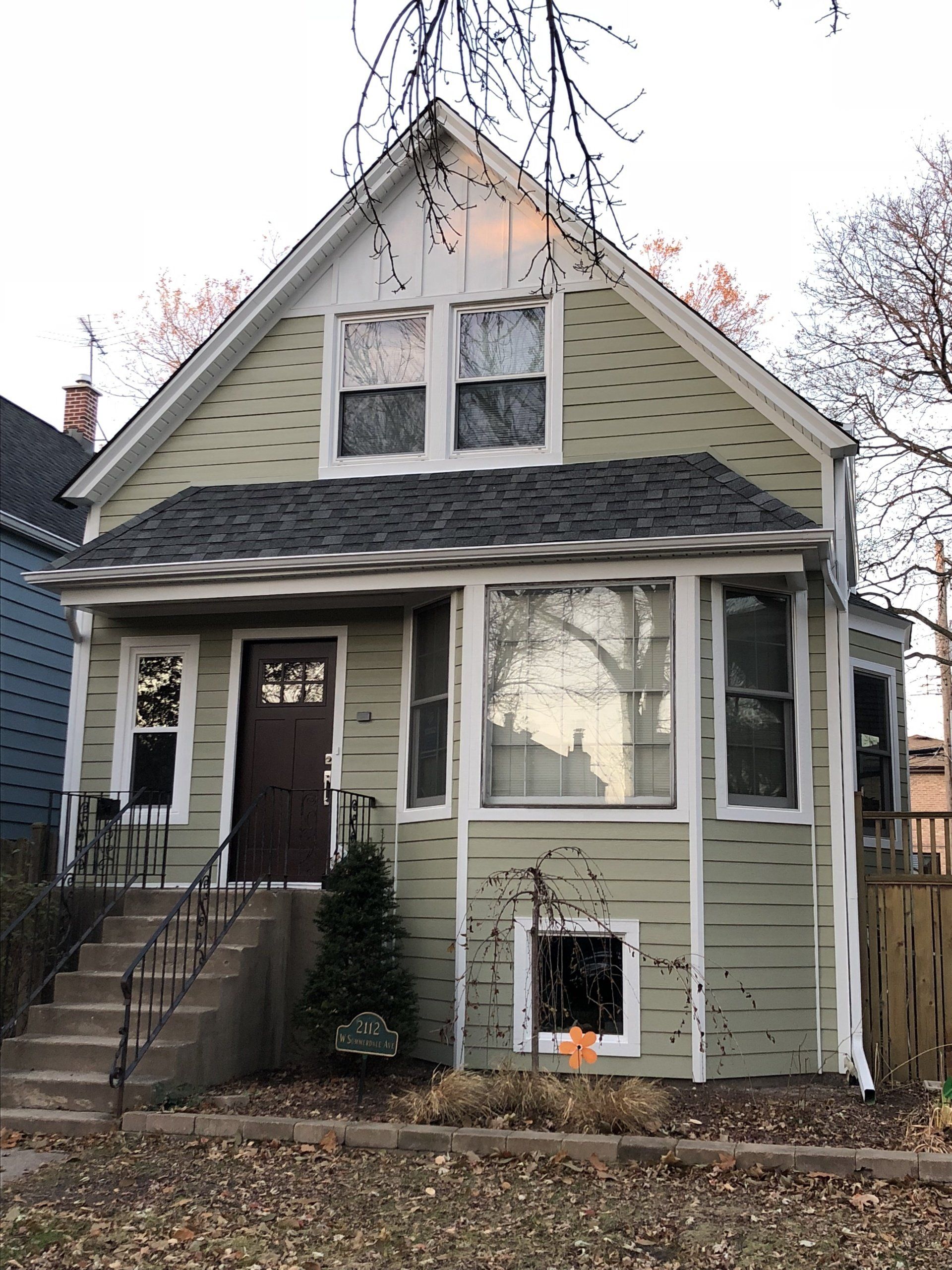 A green house with a brown door and stairs