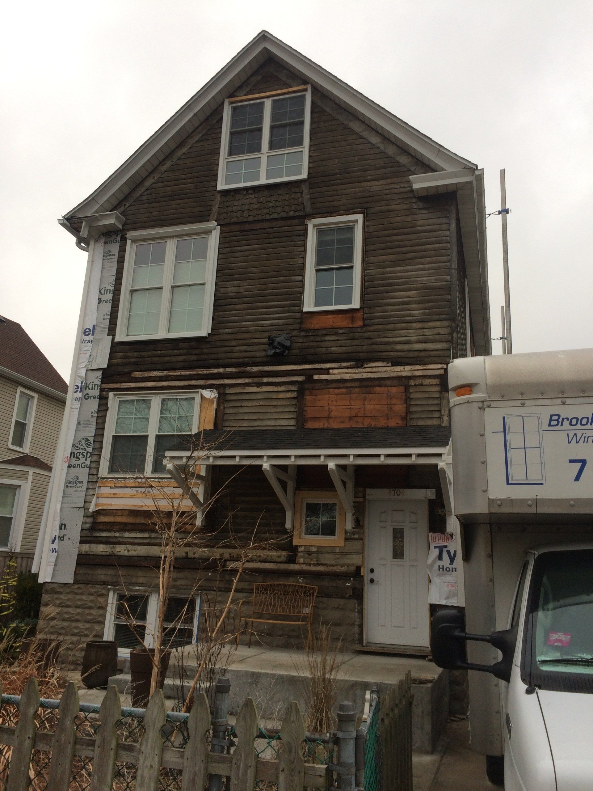 A white truck is parked in front of a house that is being demolished.