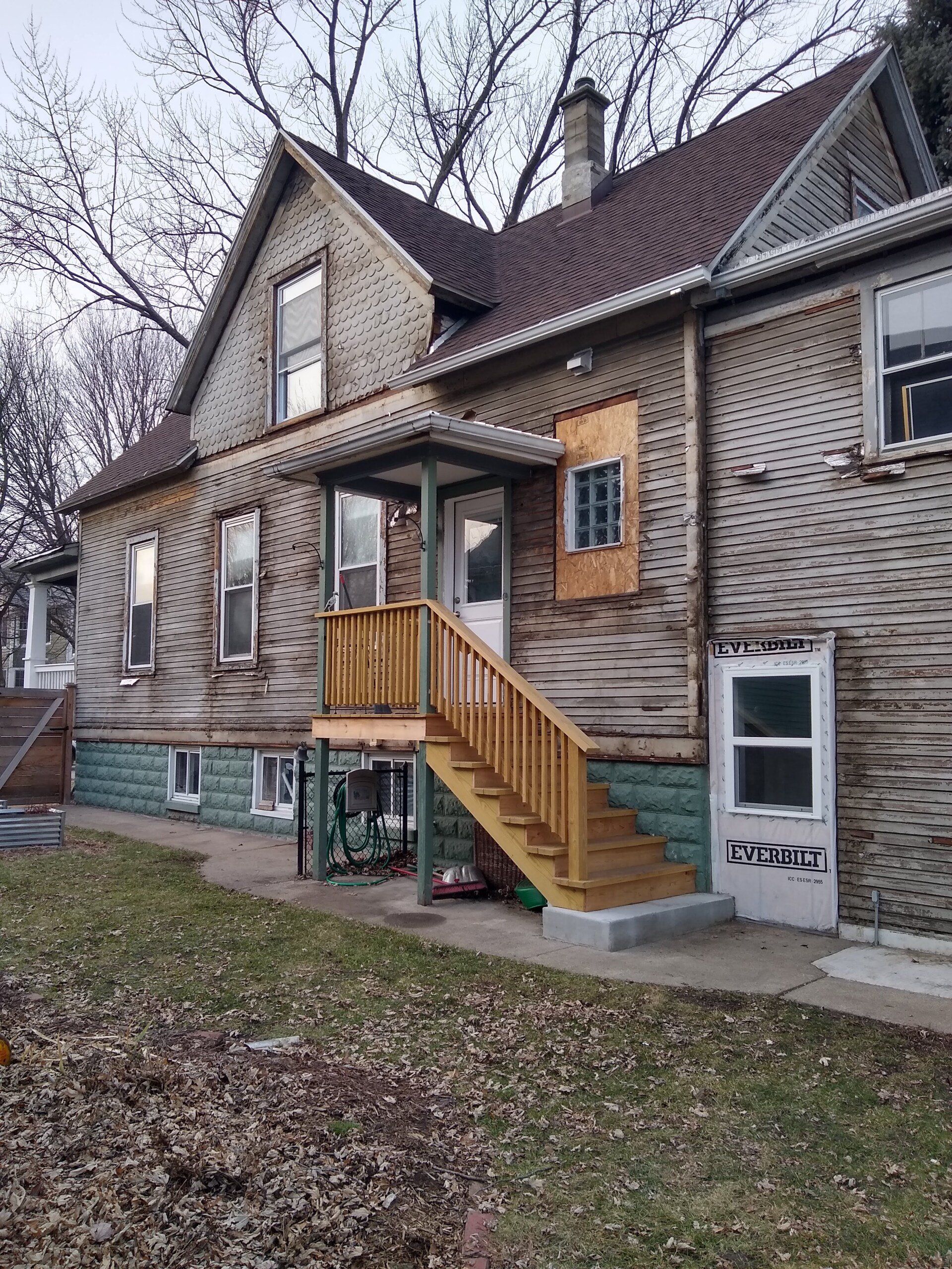 A large wooden house with stairs leading up to the front door.