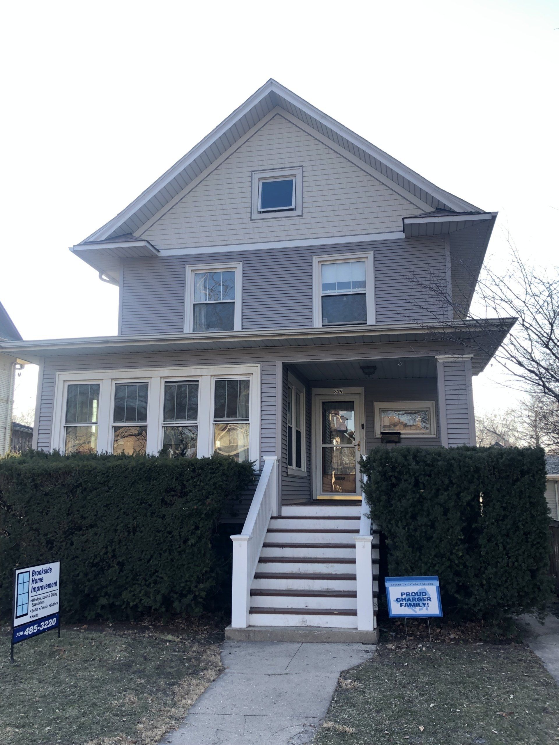 The front of a house with a for sale sign in front of it.