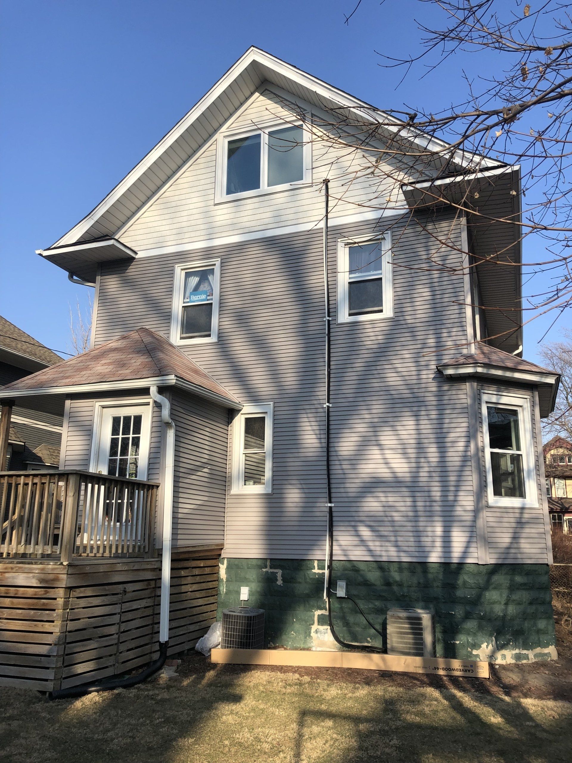 The back of a house with a deck and a blue sky in the background.