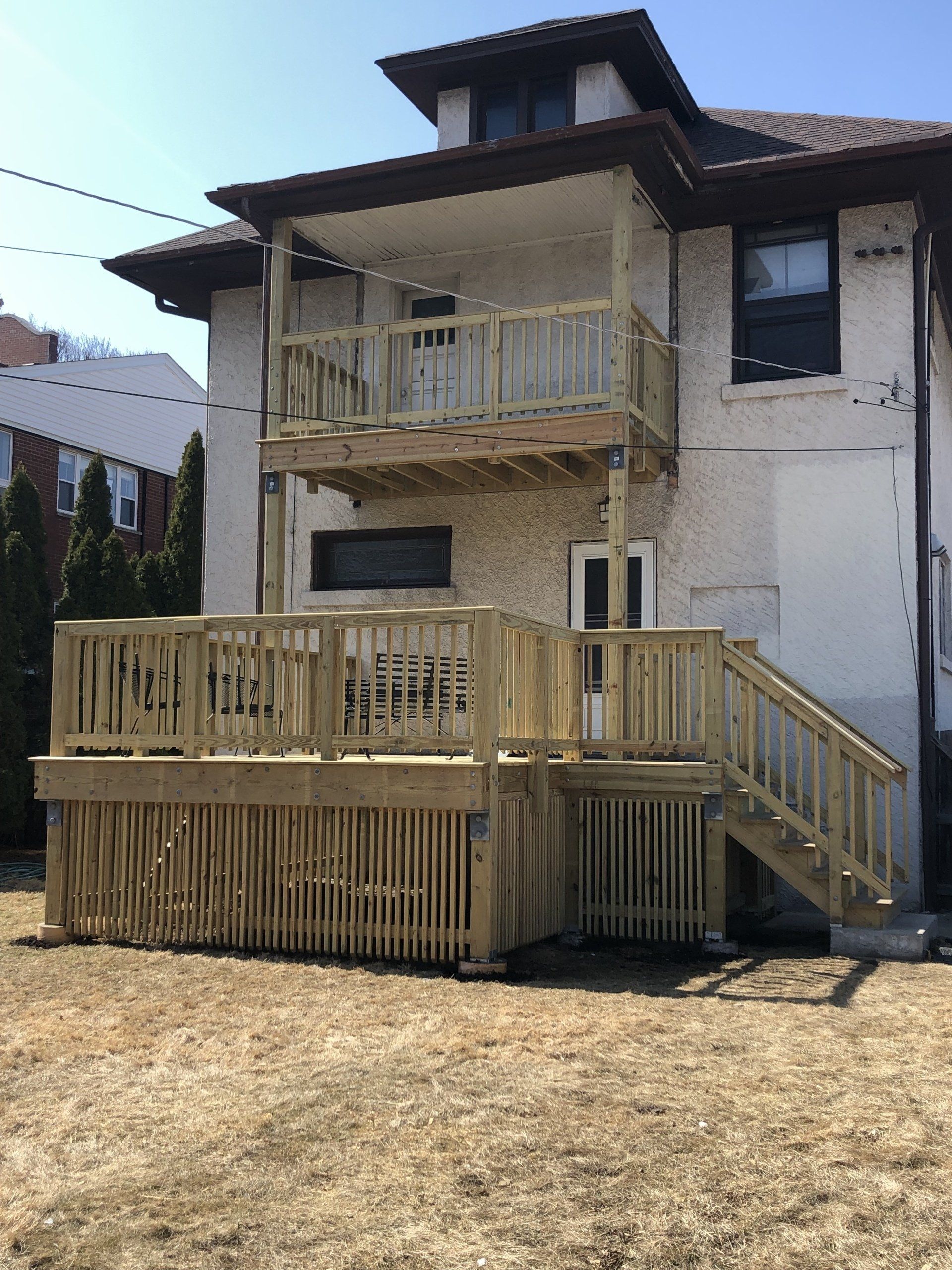 The back of a house with a wooden deck and stairs.