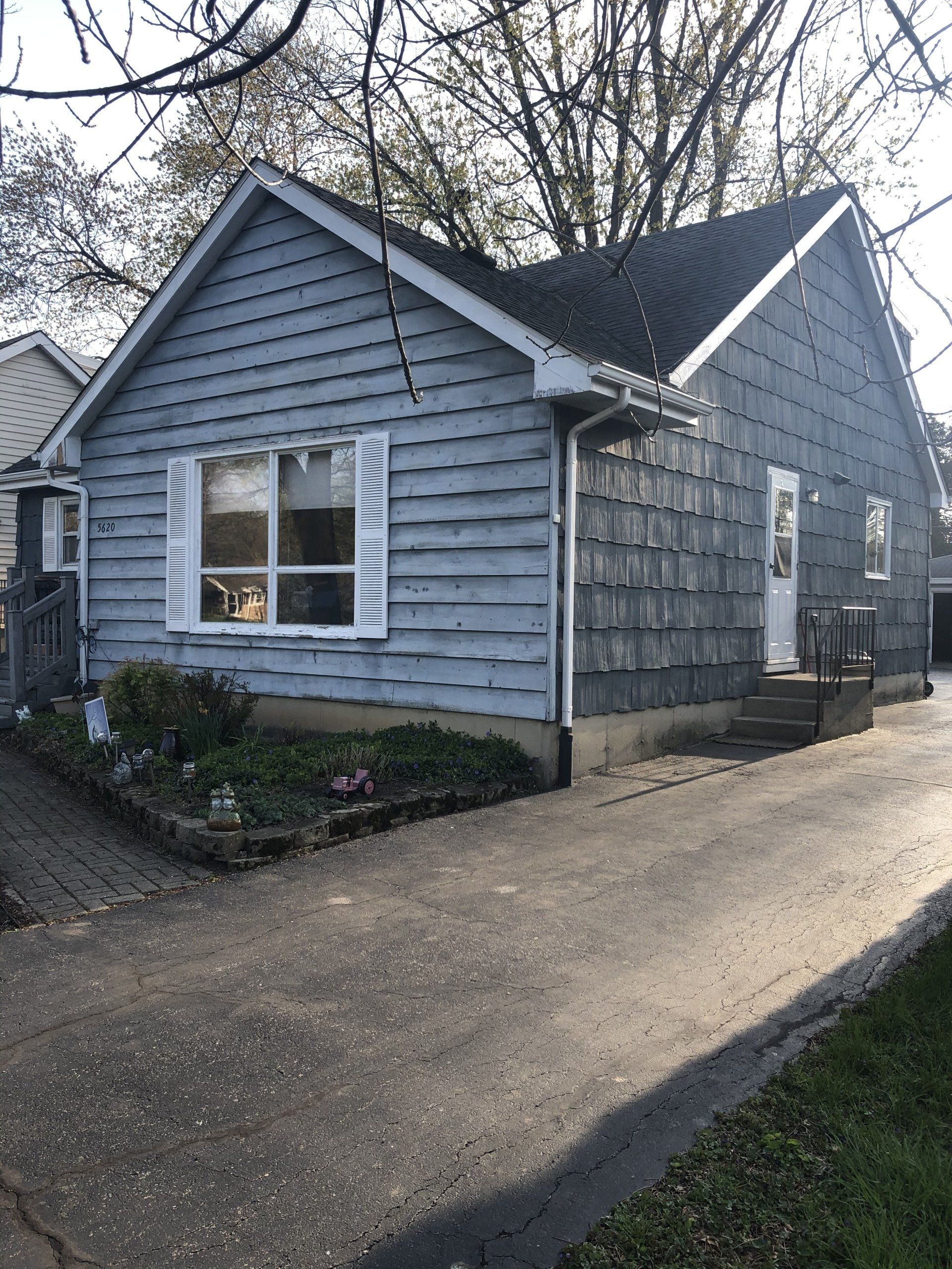 A small house with a driveway in front of it.