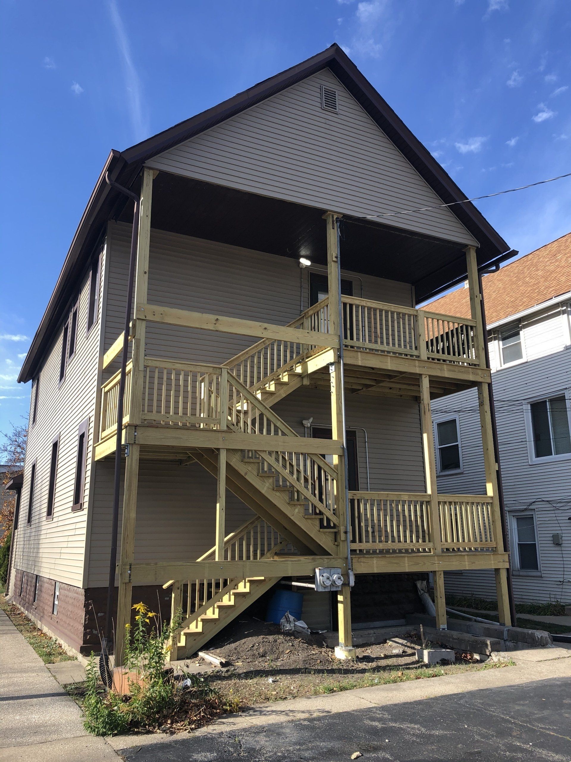 A house with a wooden deck and stairs on the second floor