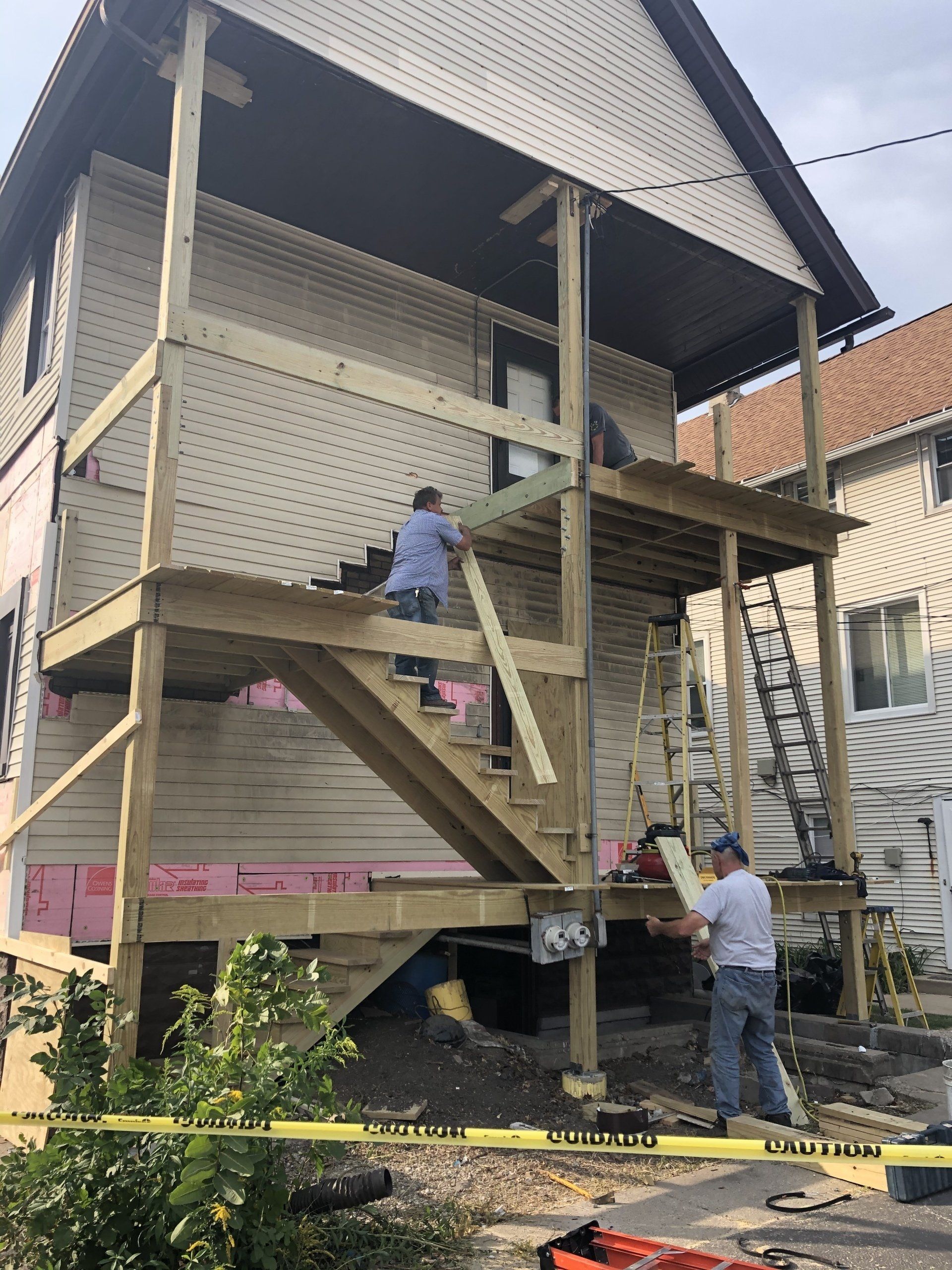 A house is being remodeled with a wooden deck and stairs.