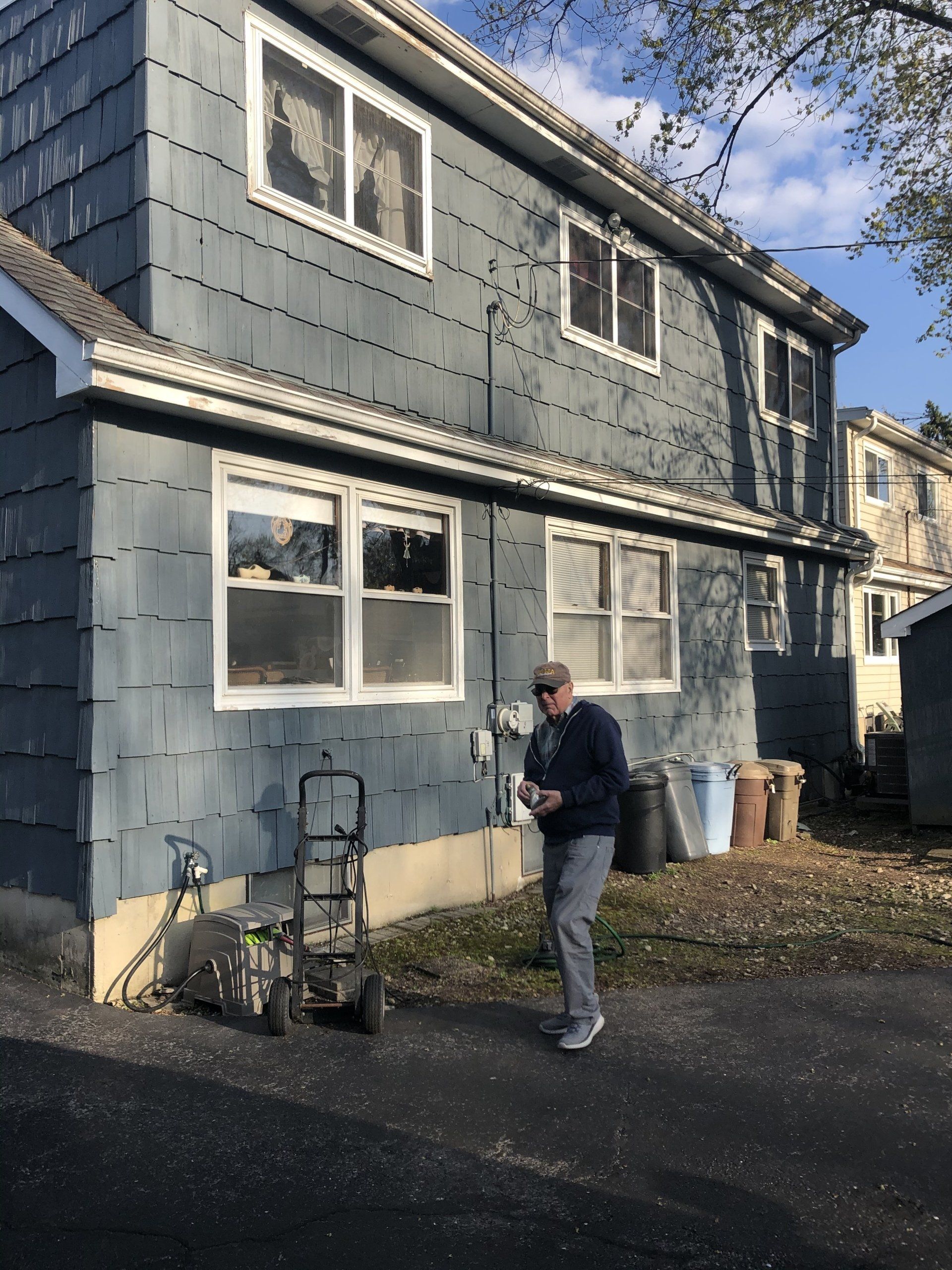 A man is standing in front of a blue house
