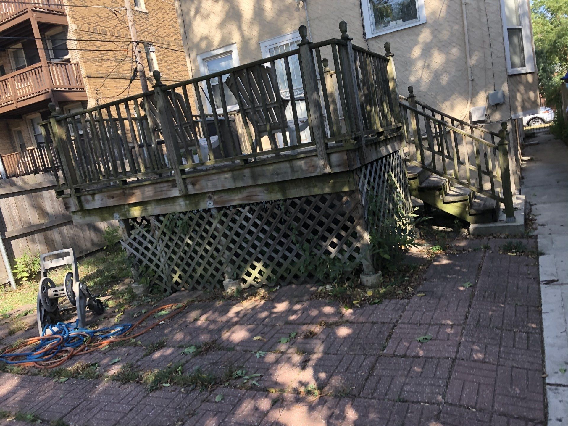 A wooden deck with stairs leading up to it is in front of a house.