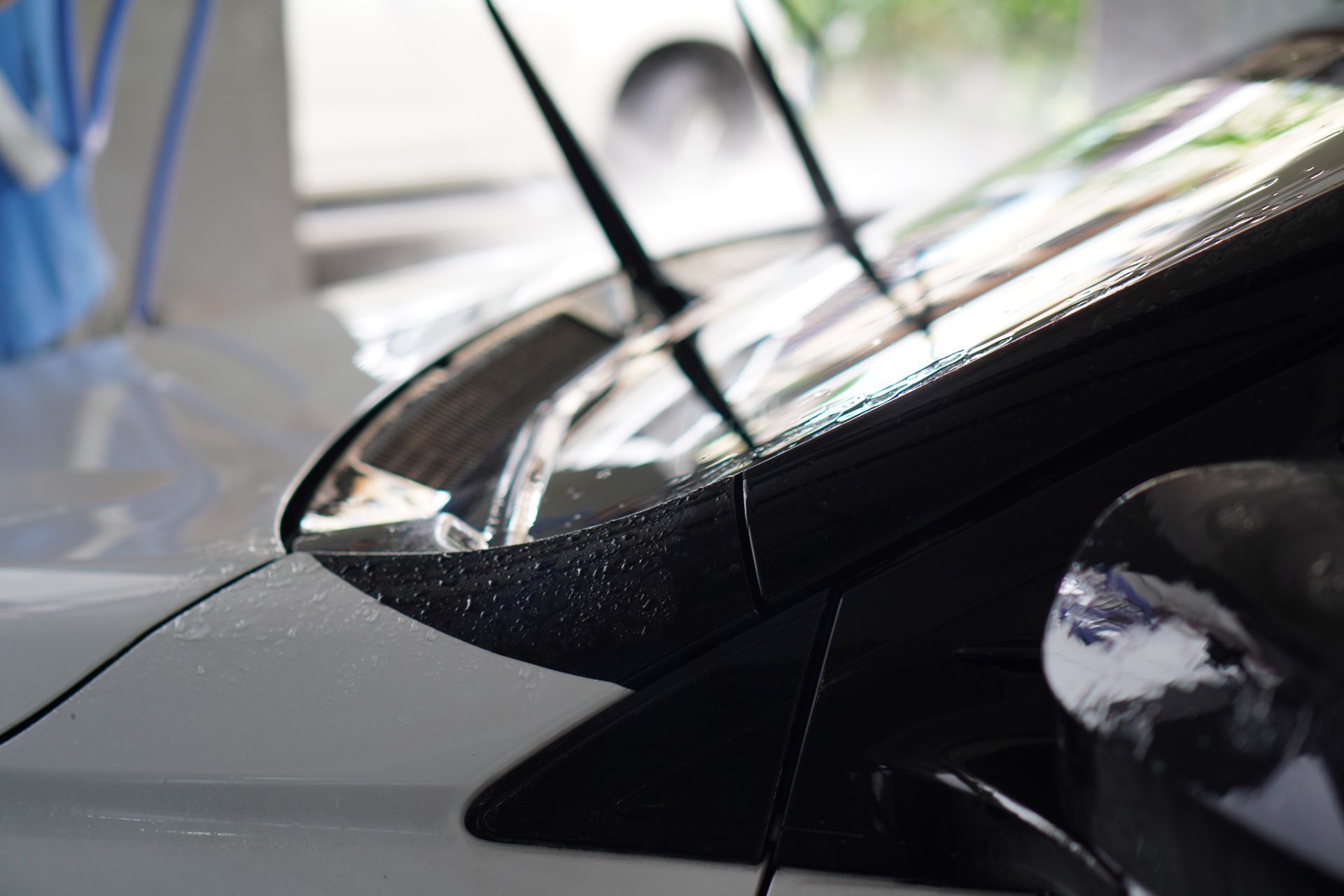 White car being washed, with windshield wipers up. Close-up shot, focus on the front.