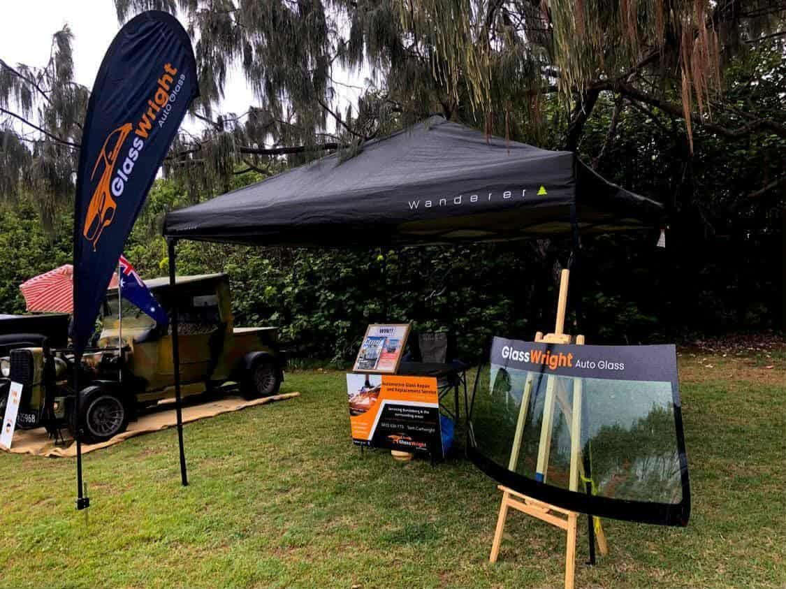A Glass Wright promotional tent with windshield display and vintage truck on grassy lawn.