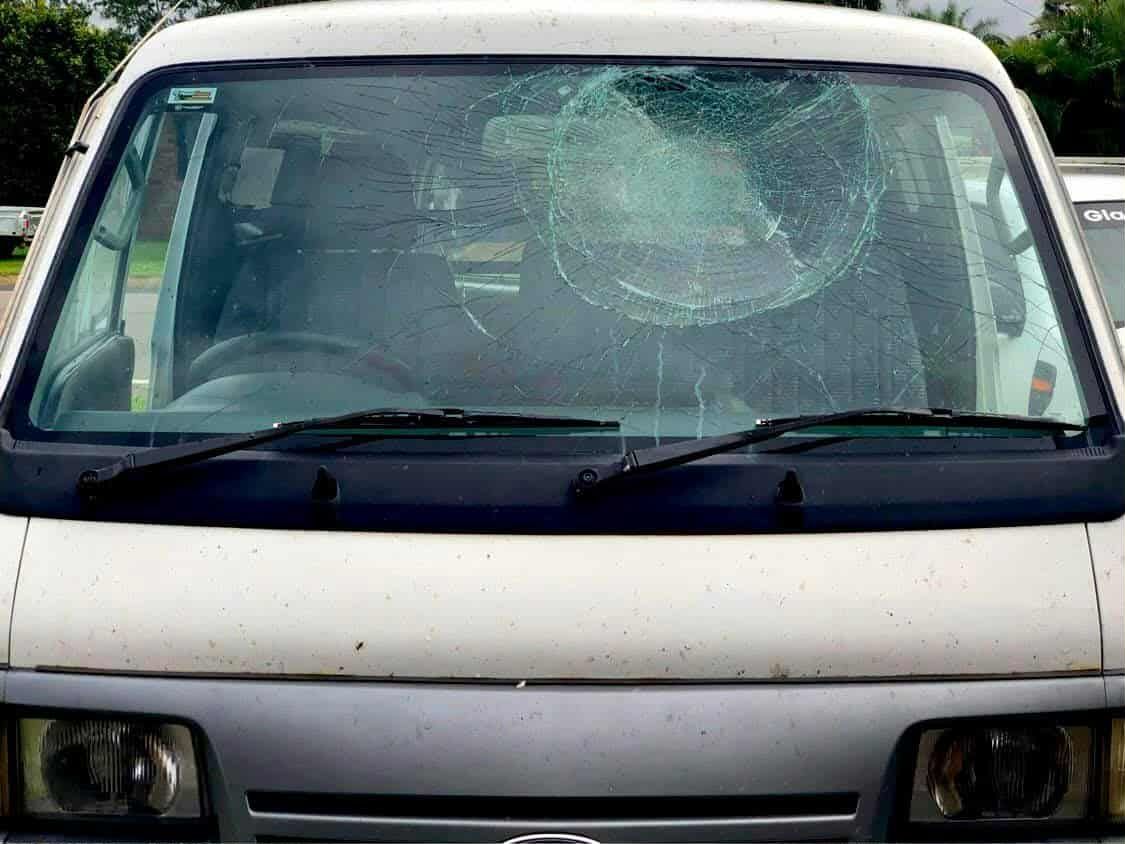 White van with severely cracked windshield; parked outdoors.