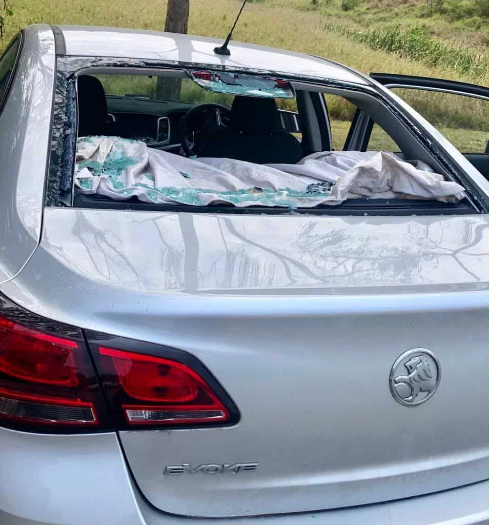 Silver sedan with shattered rear window; debris and a cloth inside.