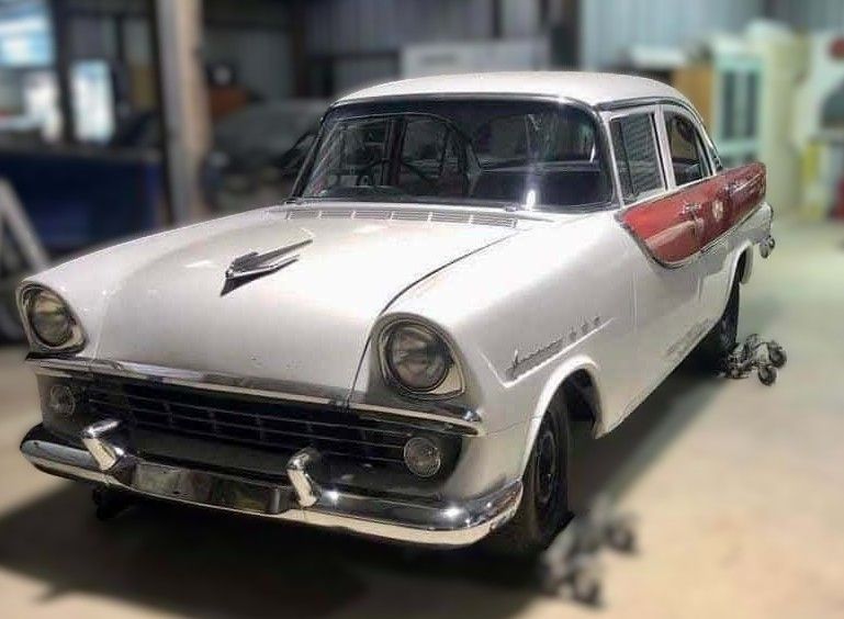 White and red vintage car indoors, black tires, chrome accents, partial view.