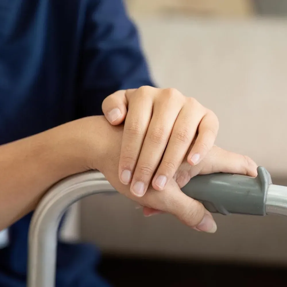 Hands resting on a walker's handle.