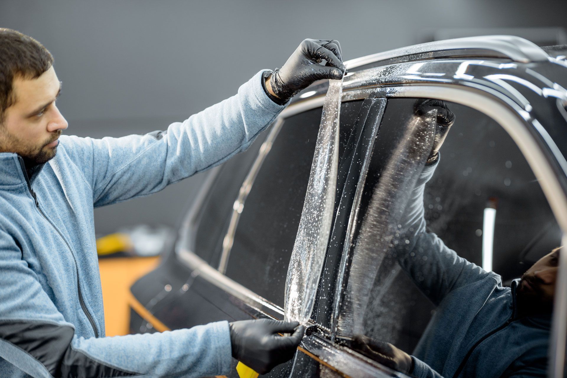 Person applying window tint to a car.