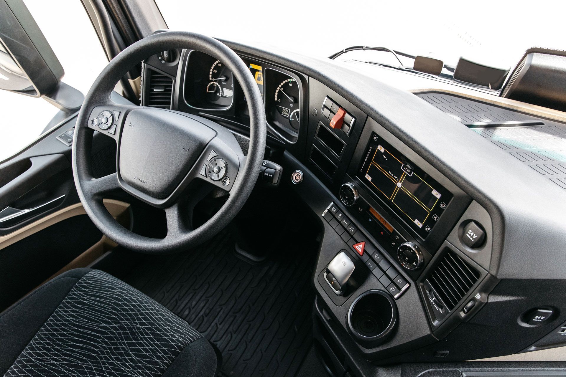 Interior view of a truck dashboard with a steering wheel, dashboard controls, and a display screen.