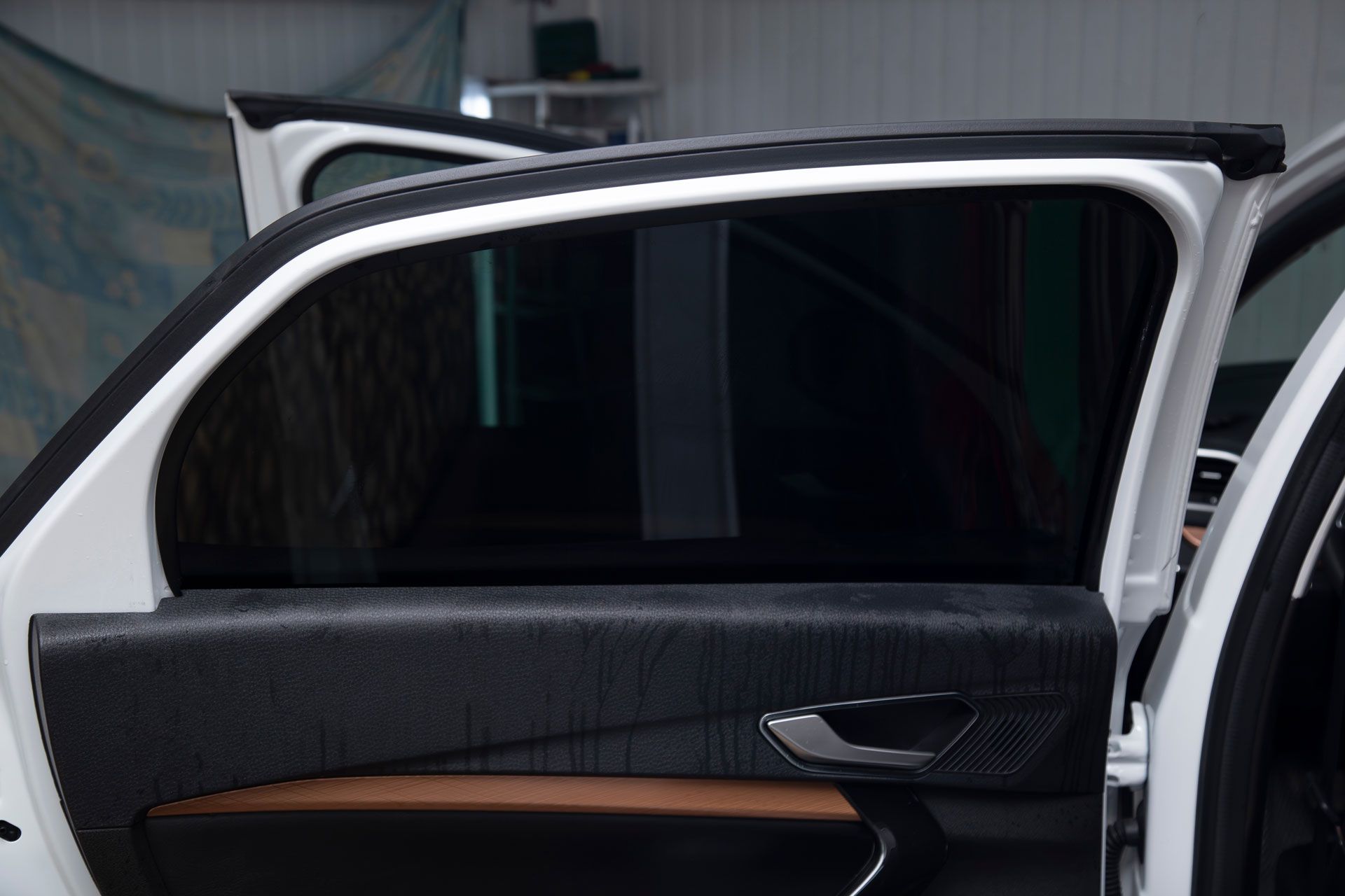 Open car door, black-tinted window, white car frame, black interior details.