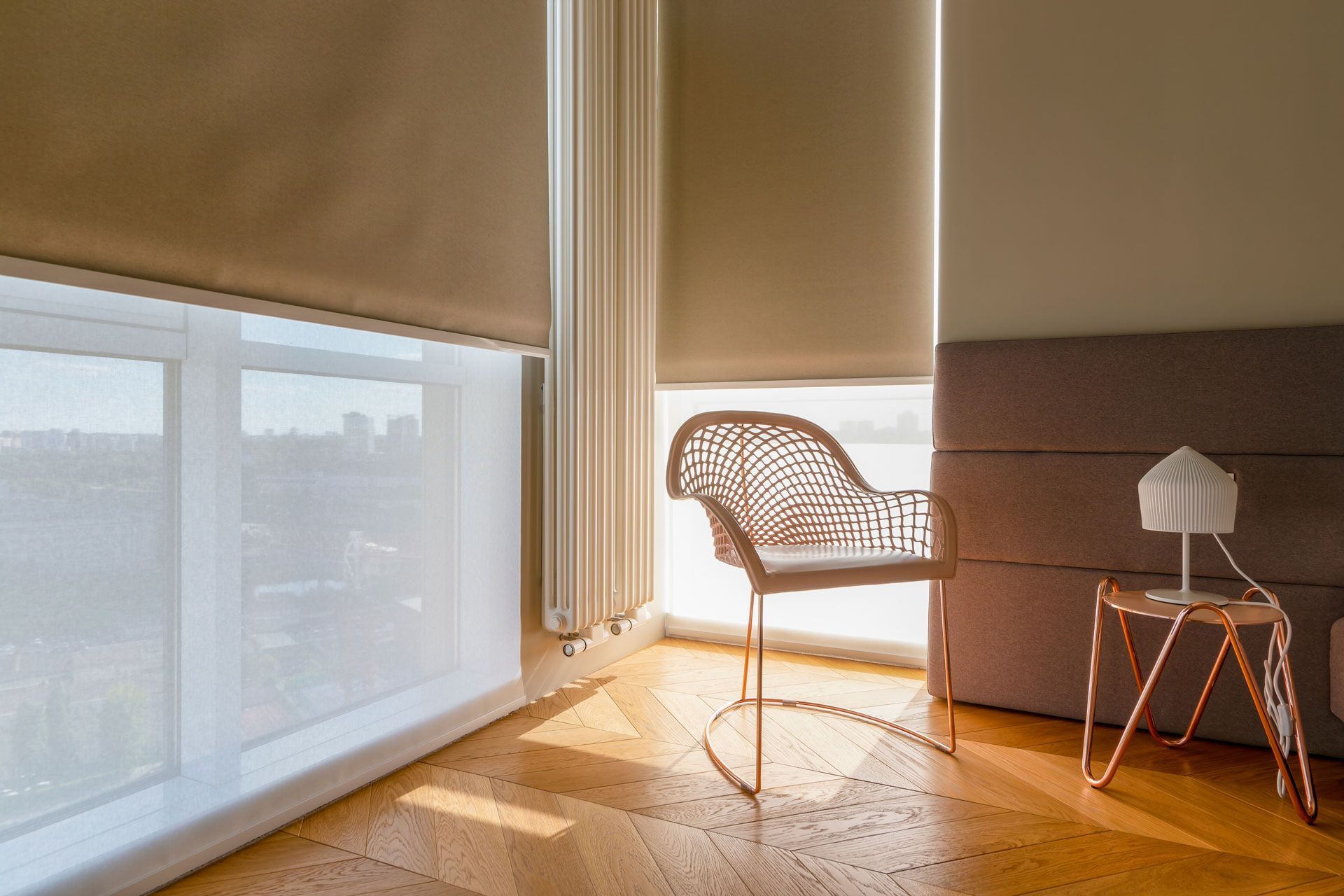 Room interior with sunlight, blinds, a chair, side table, and lamp. Wooden floor.
