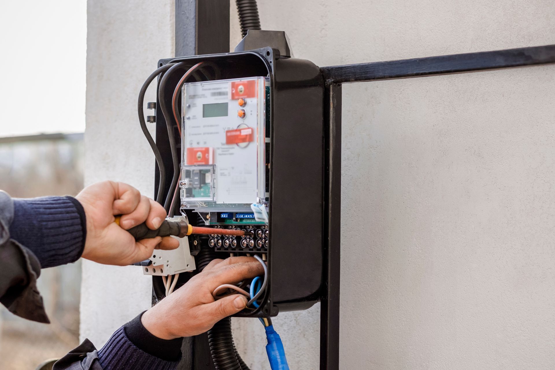 Technician wiring an electrical control panel mounted on a wall. Technician wiring an electrical control panel mounted on a wall.