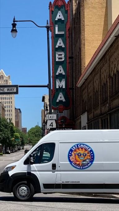 White van with a sun logo parked near the Alabama Theater in a city. 
