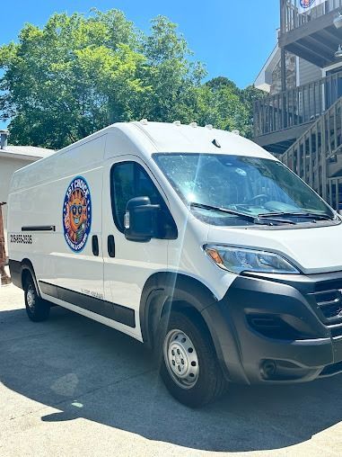 White cargo van with logo parked outdoors near a building.