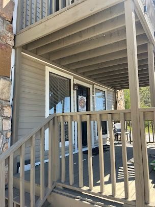 Exterior view of a building with a porch, brown siding, and a wooden staircase.