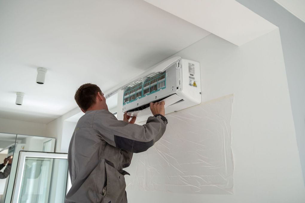 Man installing an air conditioning unit on a white wall.
