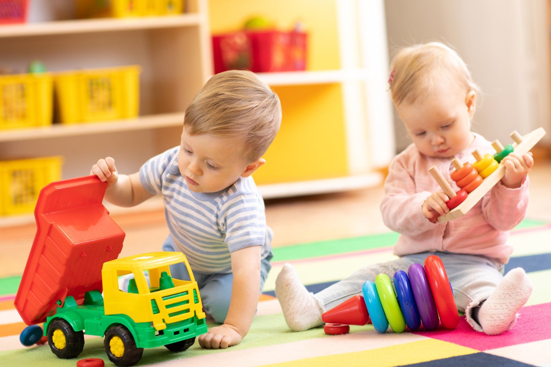 Preschool boy and girl playing on floor with educational toys
