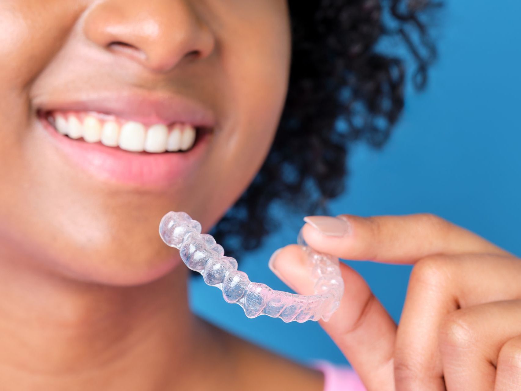 woman smiling holding clear aligners | cosmetic dentist in somerset, NJ